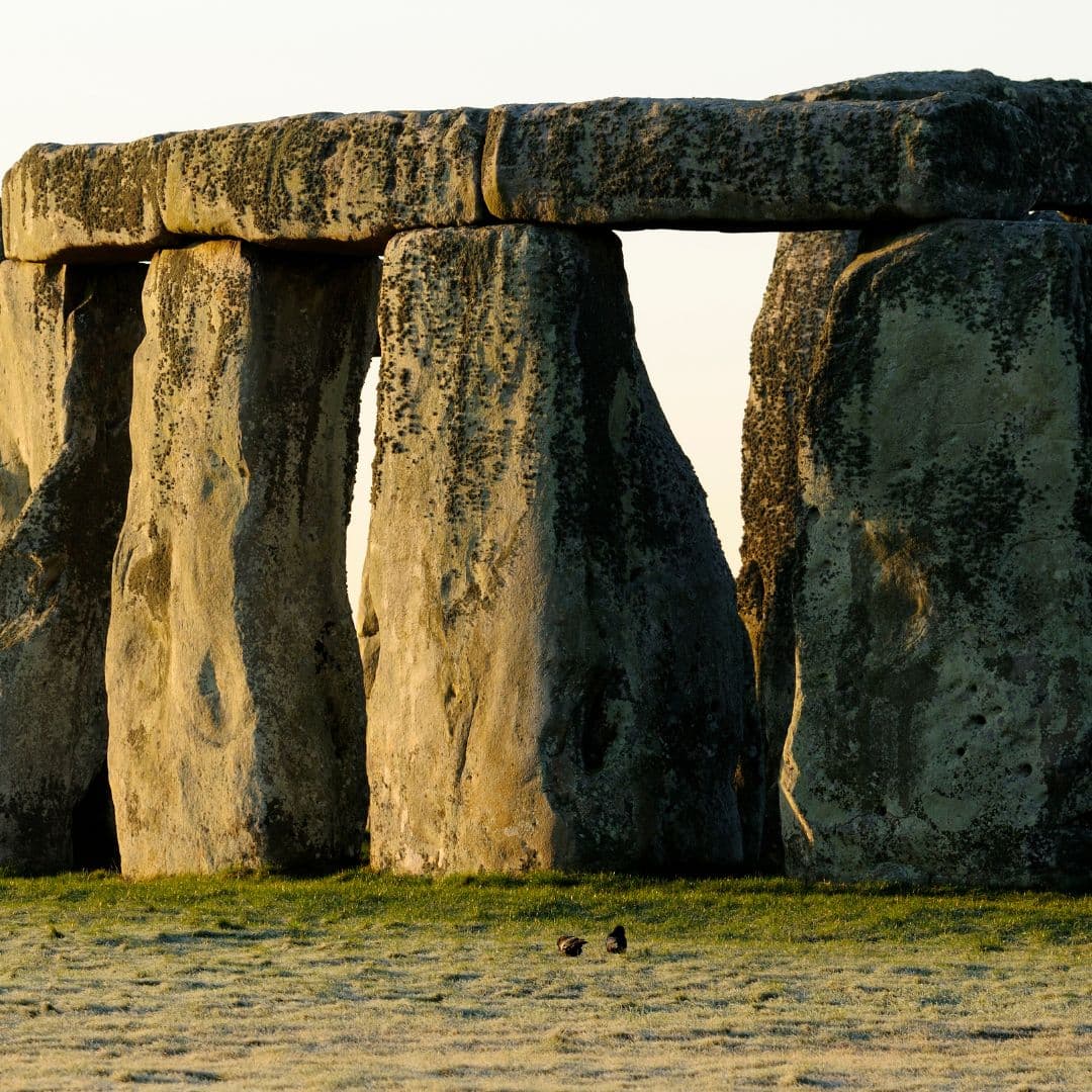 Close view of Stonehenge sarsen stones in warm evening light with a pale blue sky