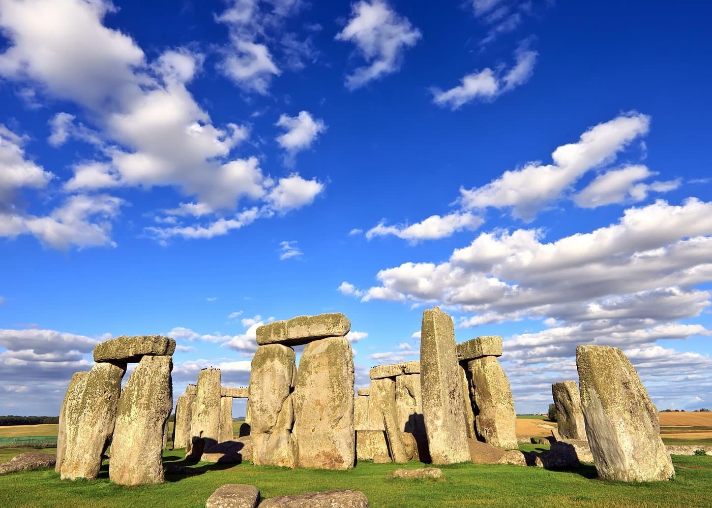 Stonehenge standing stones on a sunny day with a deep blue sky and white clouds.